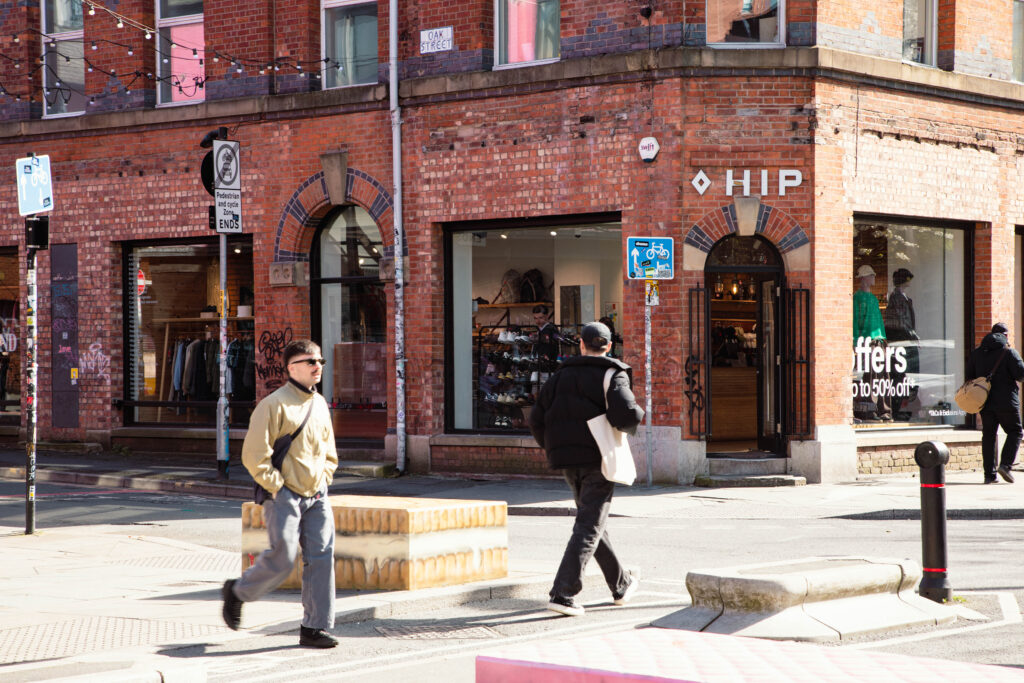 Brick building with pedestrians walking by HIP store.