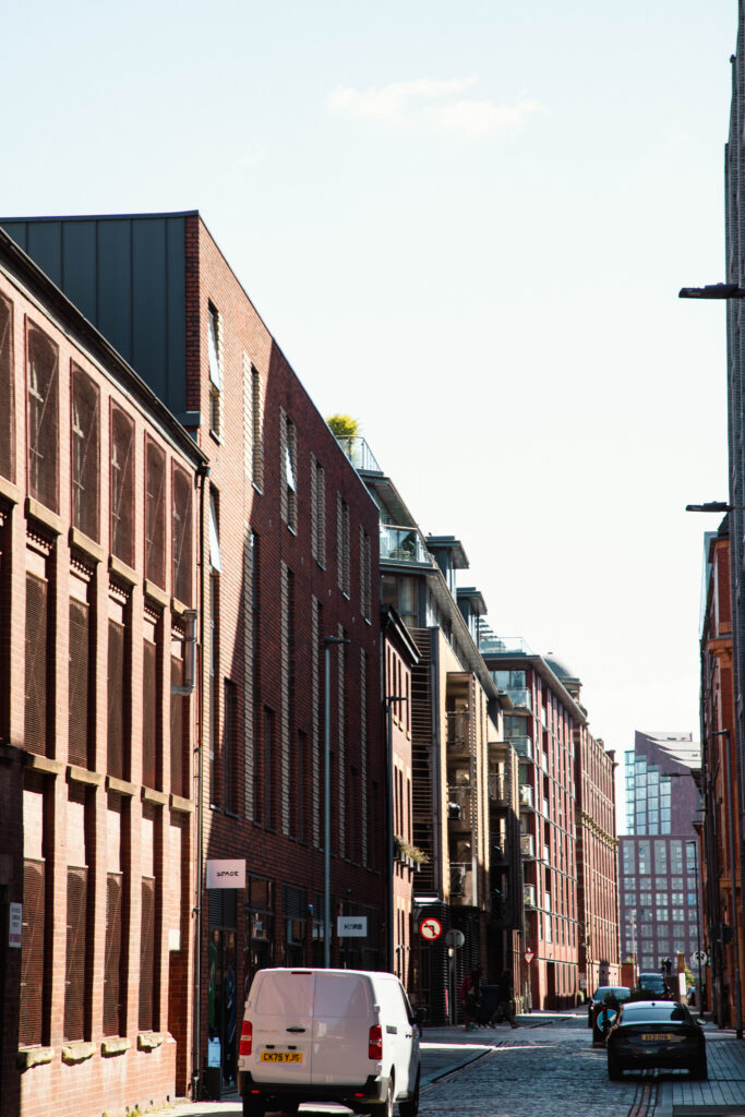 Sunny urban street with brick buildings and cars.